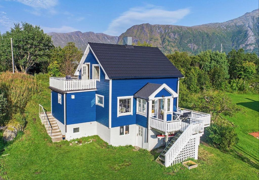 une maison bleue et blanche sur un champ vert dans l'établissement Fishermans Village Lofoten, à Alstad
