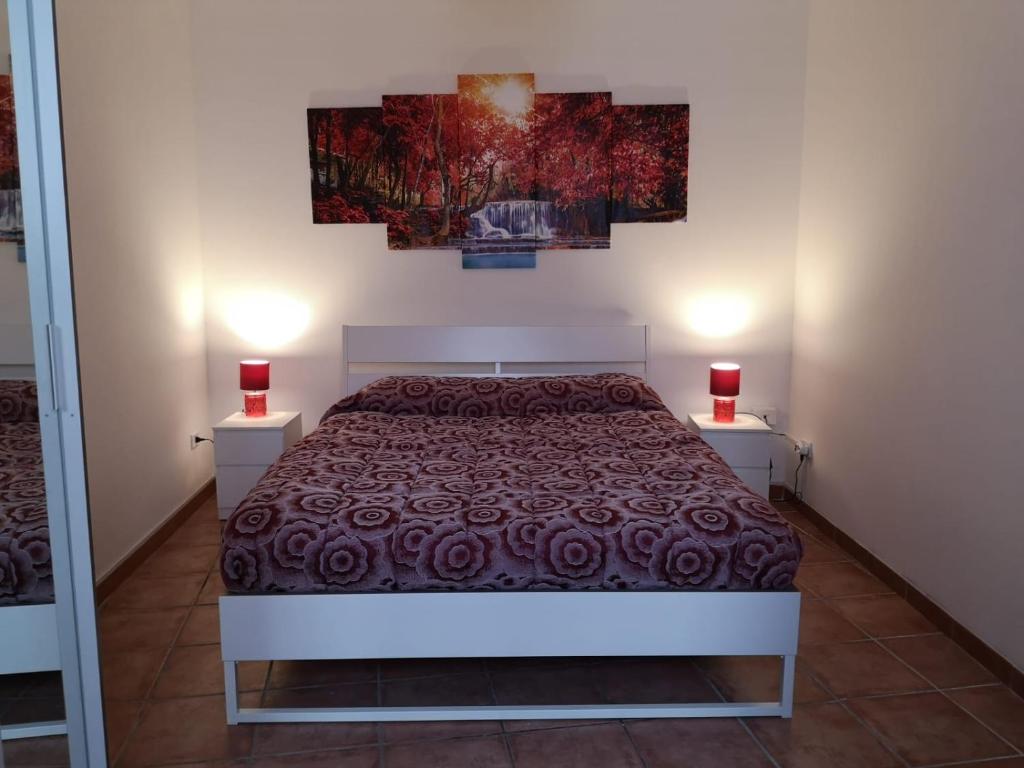 a bedroom with a bed and two red candles on two tables at Scibetta's B&B in Taranto