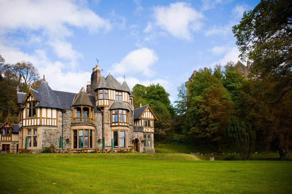 an old house with a green lawn in front of it at Knockderry Country House Hotel in Cove