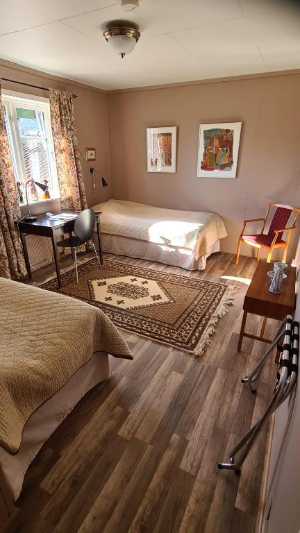 a bedroom with two beds and a desk and a table at Skogsbrynet B&B, Bredsjö Nya Herrgård in Hällefors
