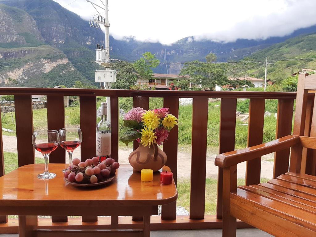 una mesa con dos copas de vino y un jarrón de flores en La Posada de Gocta en Cocachimba