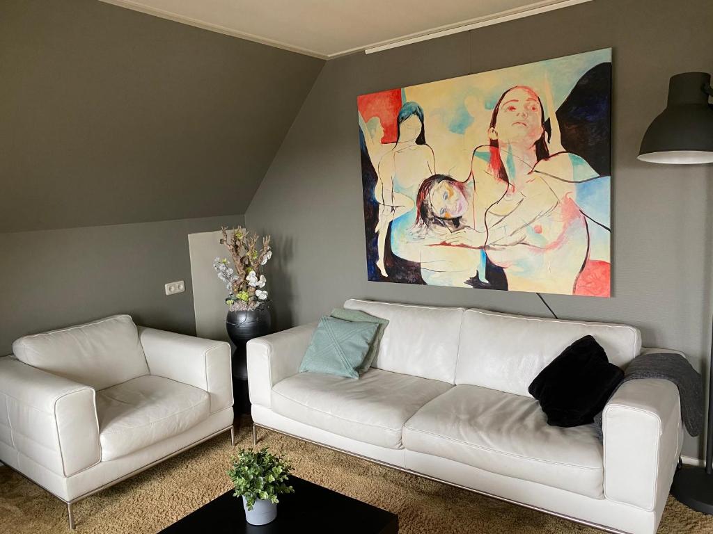 een woonkamer met een witte bank en een schilderij bij Stadsappartement Ootmarsum in Ootmarsum