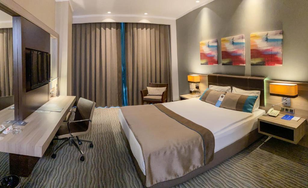 um quarto de hotel com uma cama grande e uma secretária em Ostimpark Business Hotel em Ancara