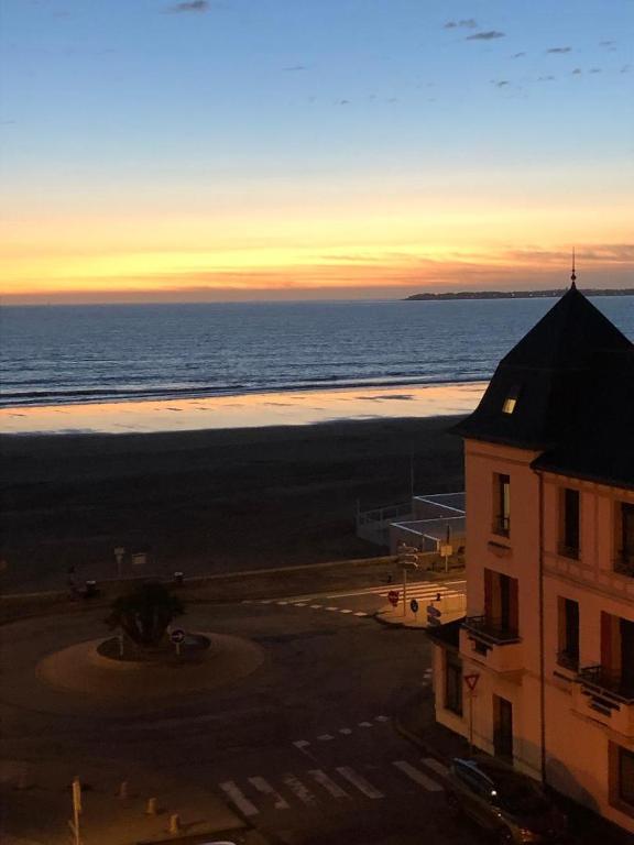 - une vue sur un bâtiment et l'océan au coucher du soleil dans l'établissement LES CEDRES, Résidence LES OCEANES, à Pornichet