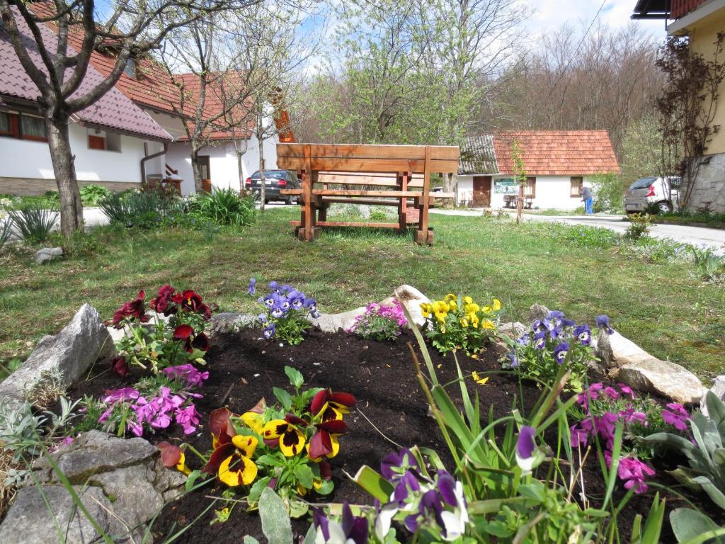 a park bench in a garden with flowers at House Katja in Jezerce