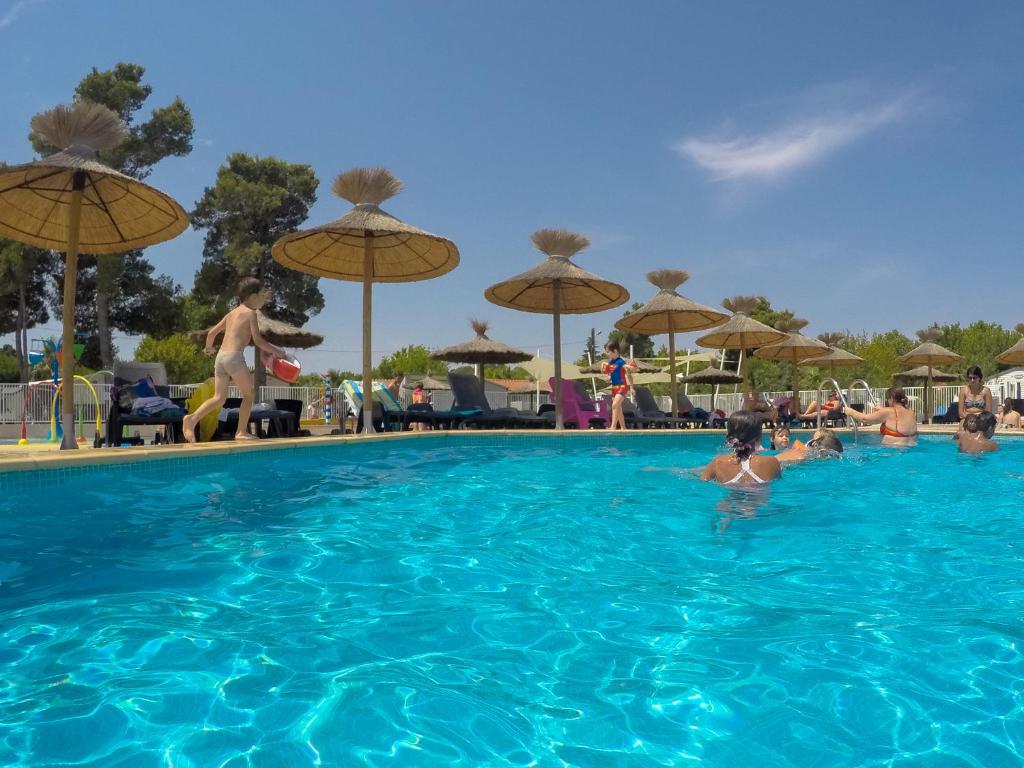 een groep mensen in een zwembad met parasols bij Mobile home De Luxe St Cyprien in Saint-Cyprien