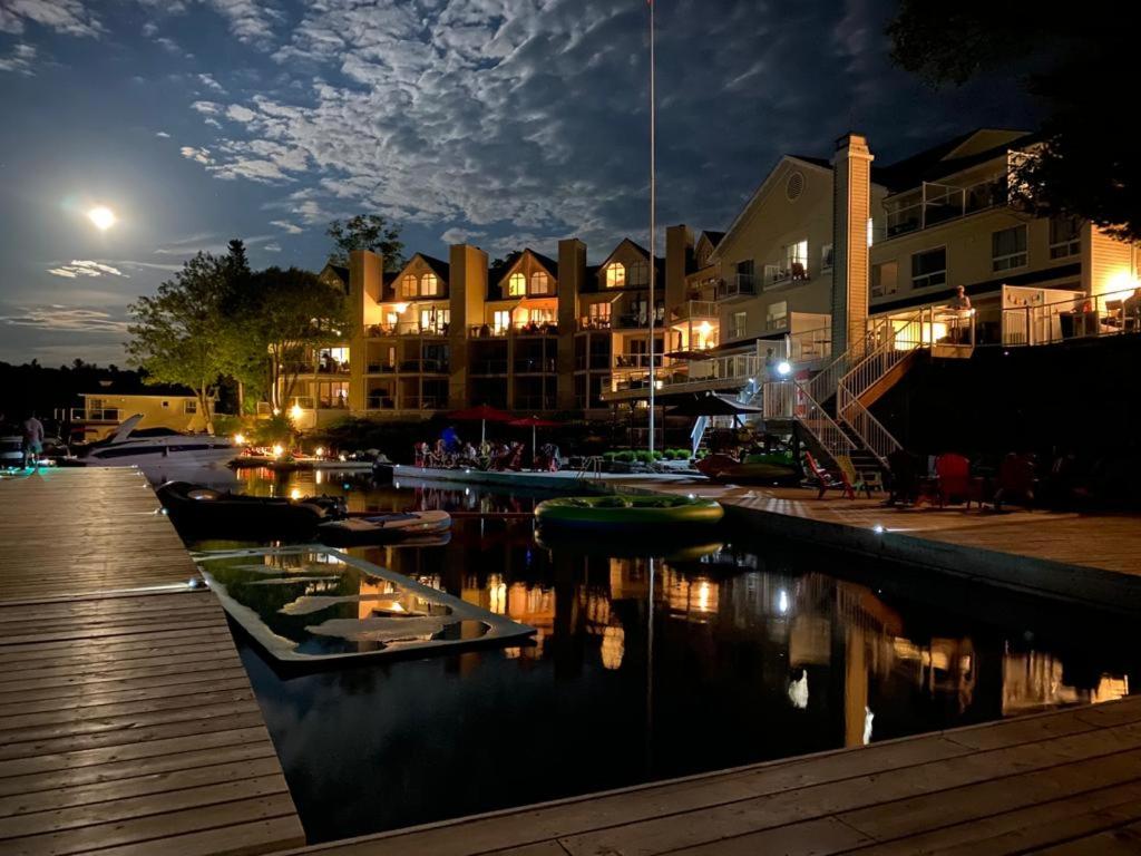 Muskoka Lakes Hotel and Resorts في ميناء كارلينج: مجموعة من القوارب رست في المارينا في الليل