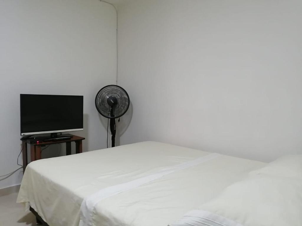 a white bedroom with a bed and a flat screen tv at Apartamento completo medellin in Medellín