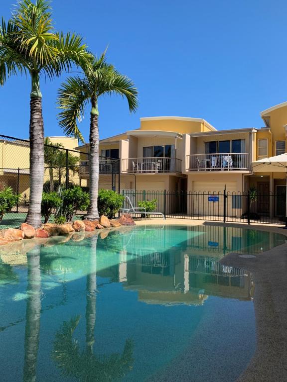 a swimming pool with palm trees in front of a building at Coolum Beach Getaway Resort in Coolum Beach
