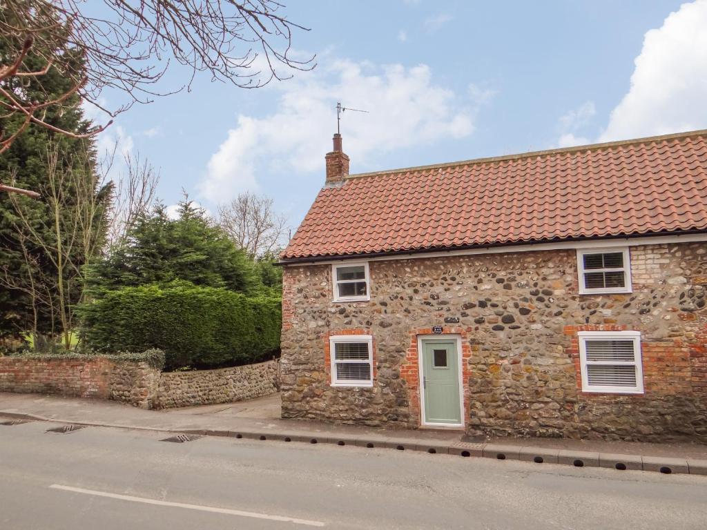 a stone house with a red roof on a street at Cobble Cottage in Hornsea