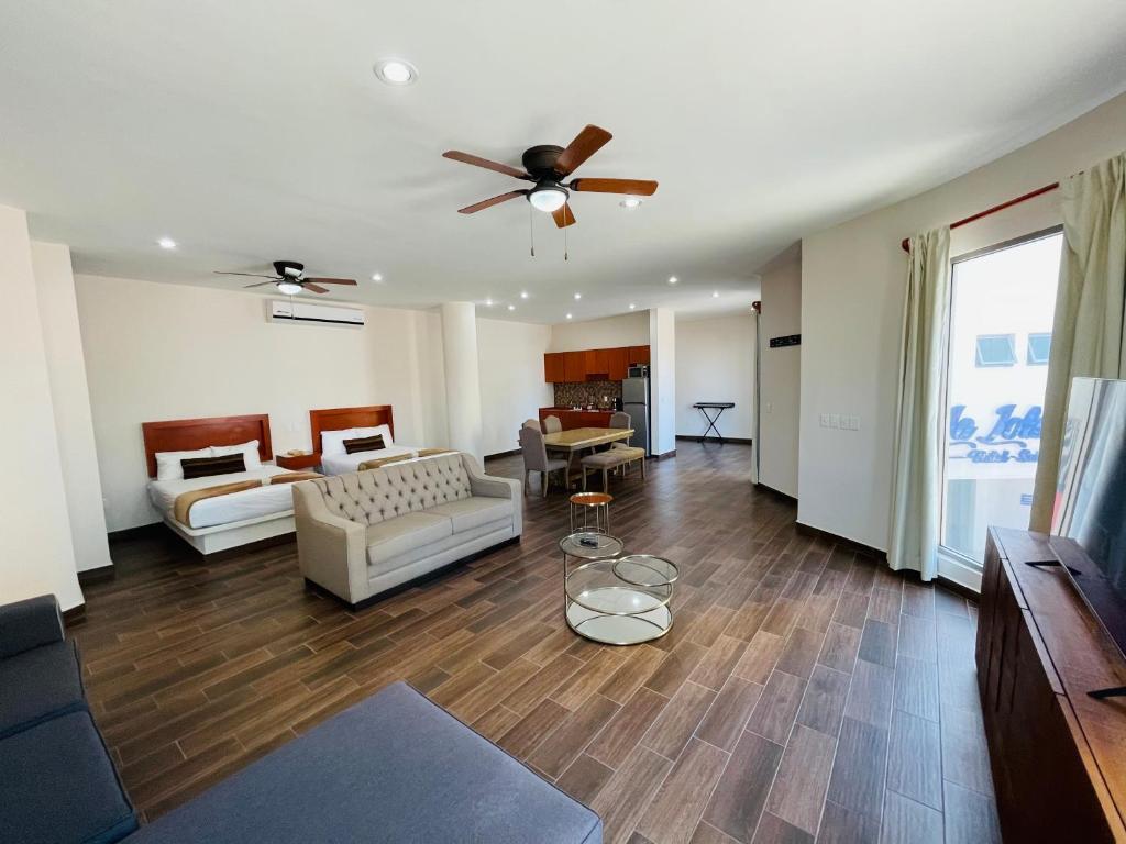 La Lola Hotel & Suites في مازاتلان: غرفة معيشة مع أريكة ومروحة سقف