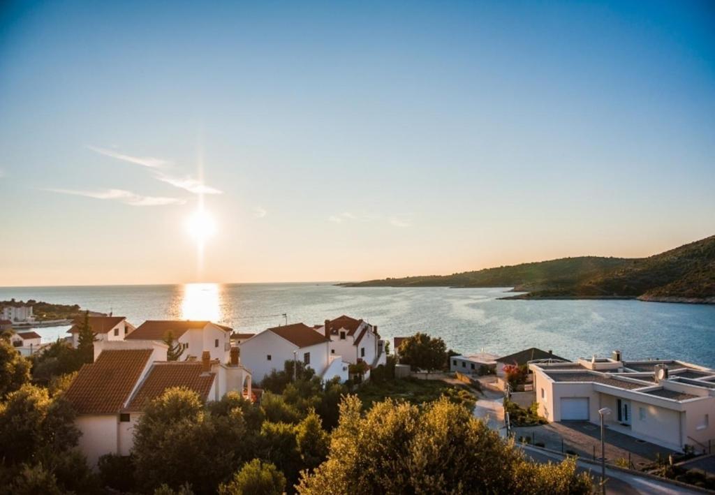 a village on the water with the sun setting at Apartments AnteV - 80m from the sea in Sevid