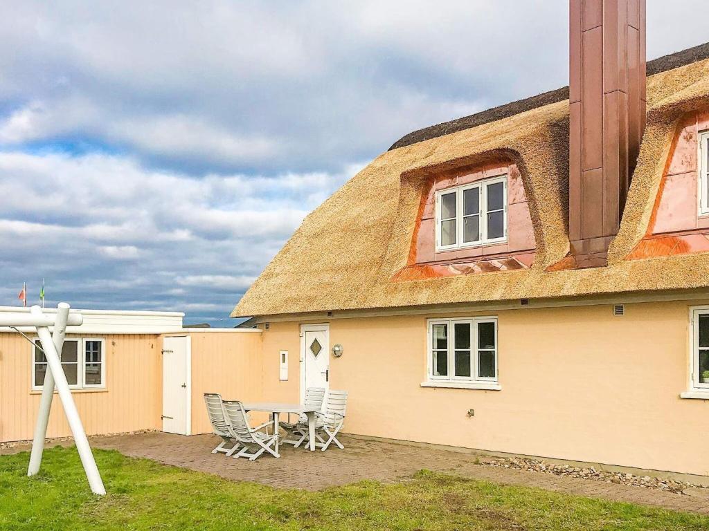a house with a thatched roof with chairs outside at 8 person holiday home in Bl vand in Blåvand