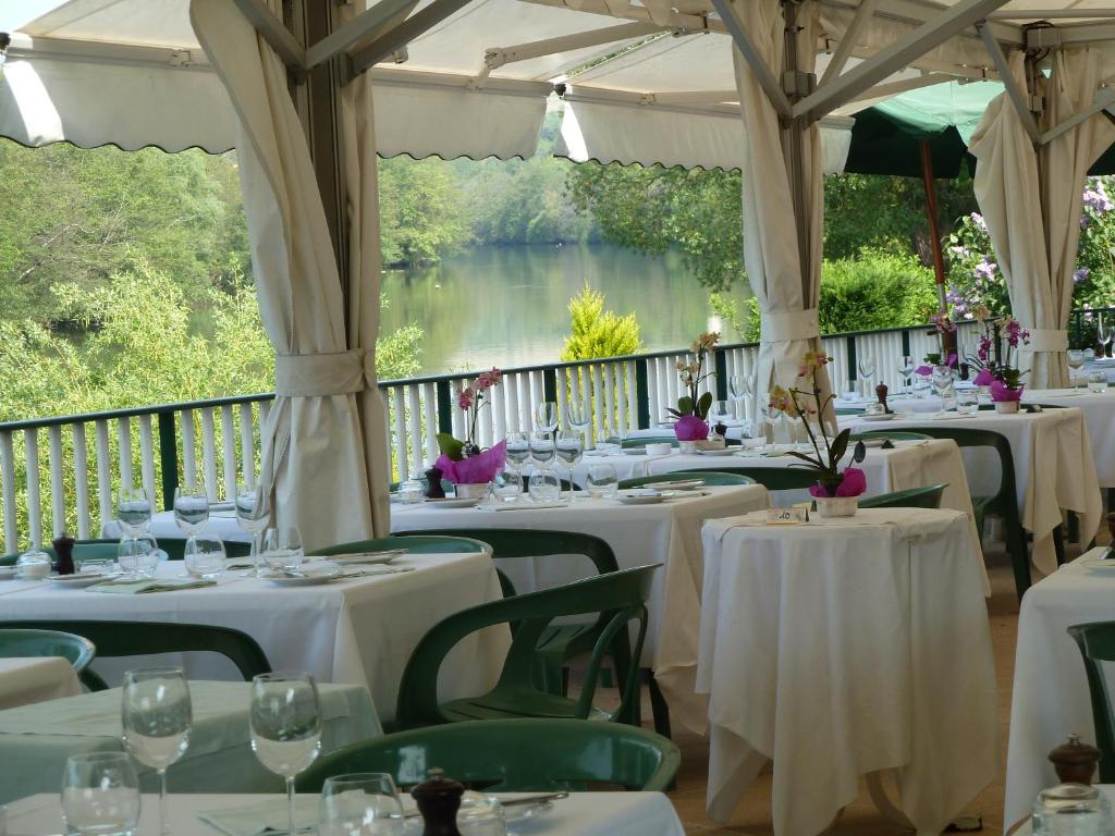 rzędu stołów z białymi tkaninami stołowymi i widokiem na jezioro w obiekcie Auberge Les Tilleuls w mieście Vincelottes