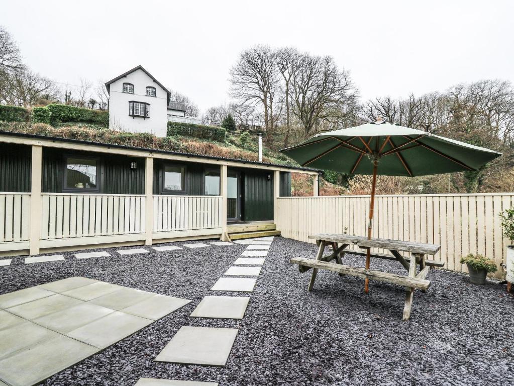 a picnic table with an umbrella and a bench at Y Felin - Celyn in Borth