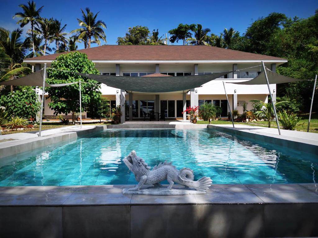a swimming pool with a dragon statue in front of a house at Sunset Cove Beach & Dive Resort in Romblon