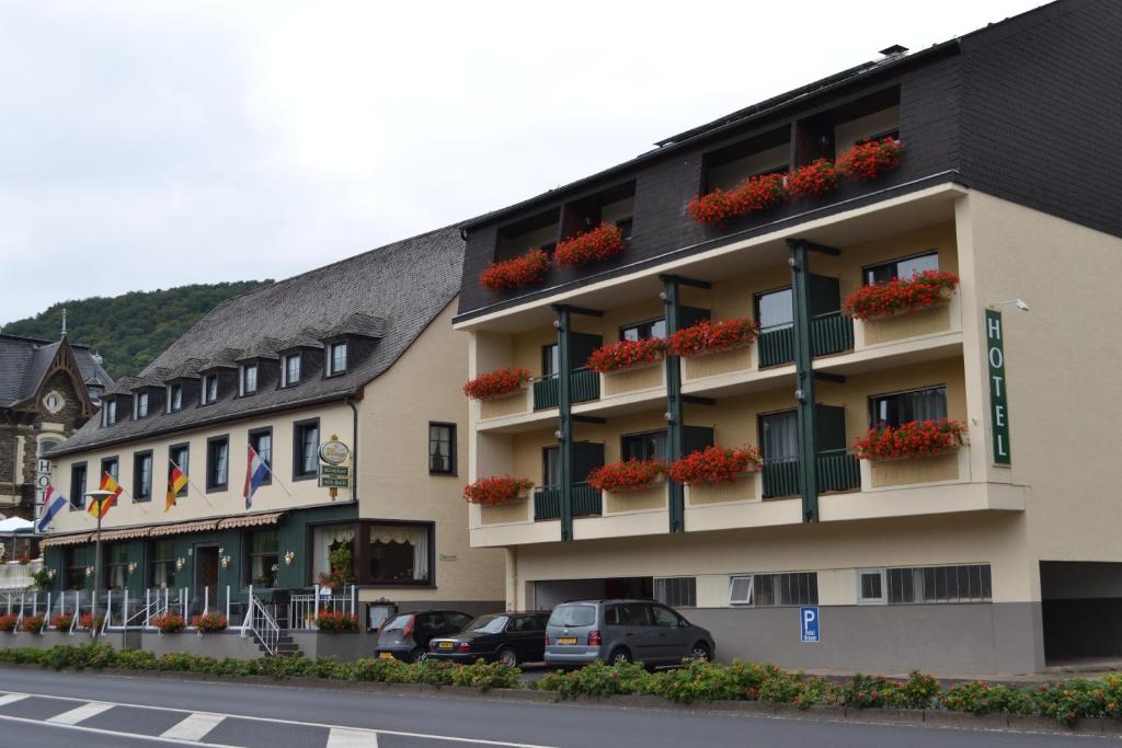 a building with flowers on the balconies and cars parked at Hotel Brauer in Treis-Karden