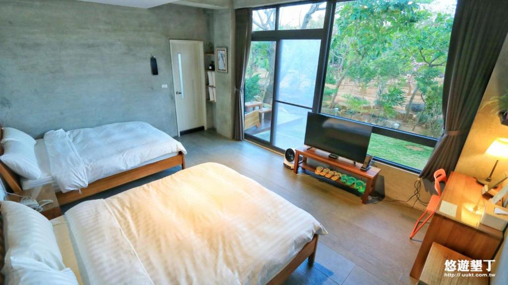 a bedroom with two beds and a flat screen tv at Lin's Forest in Hengchun South Gate