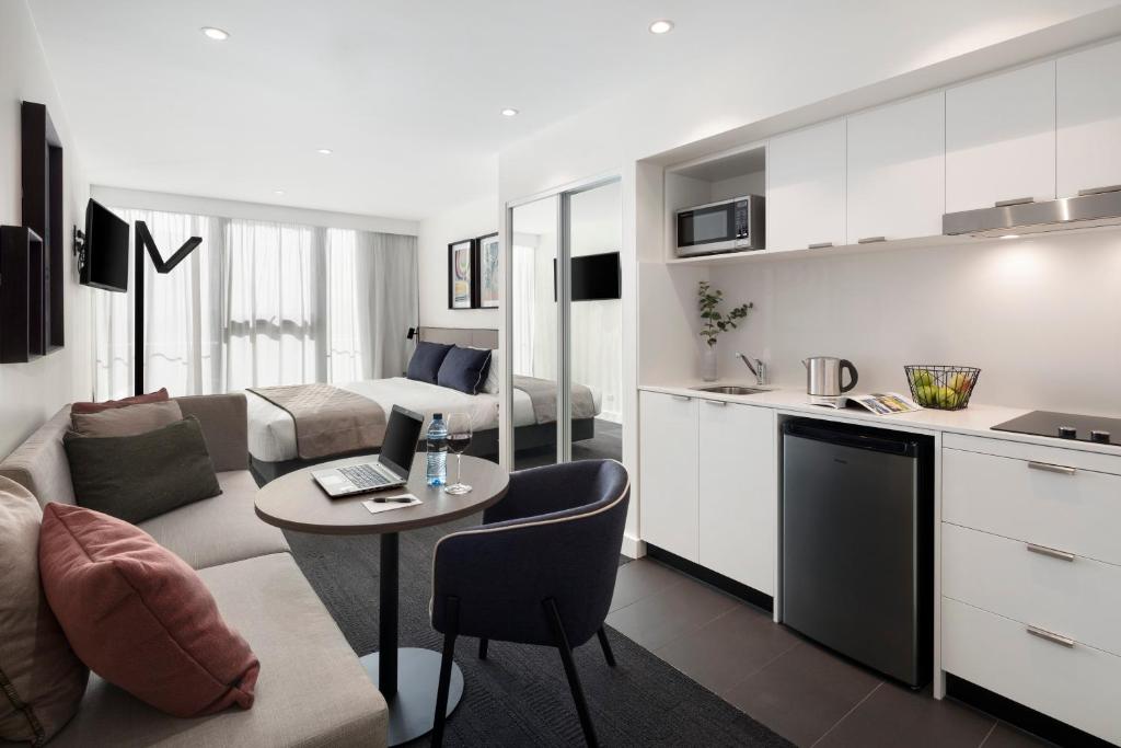 a kitchen and a living room with a couch and a table at Quest St Kilda Road in Melbourne