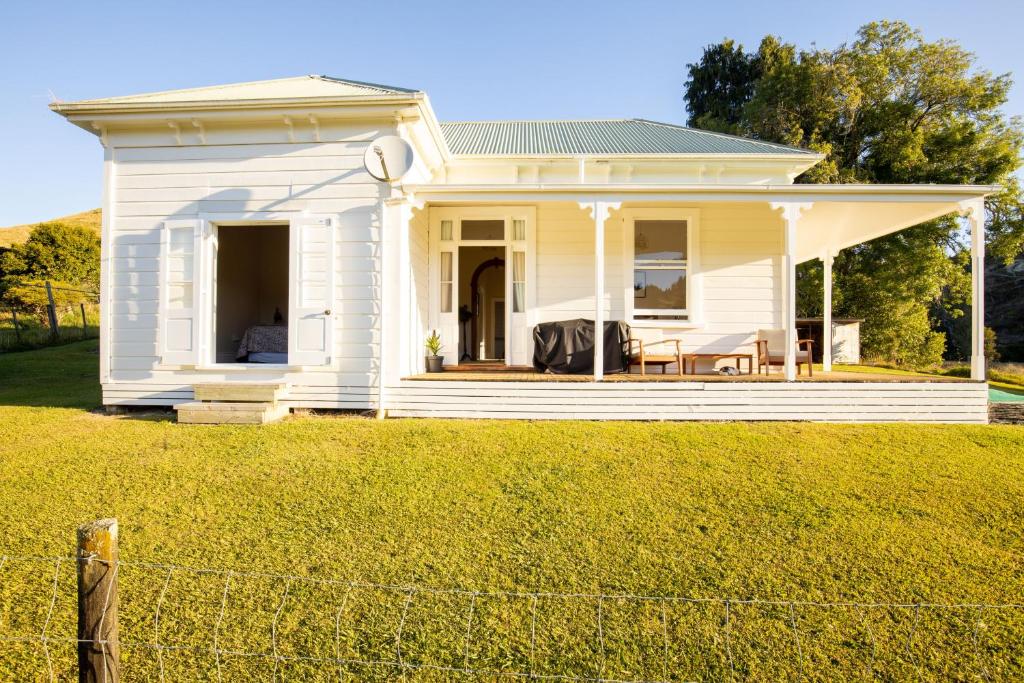 uma casa branca com uma cerca à frente. em Mill House em Pohokura