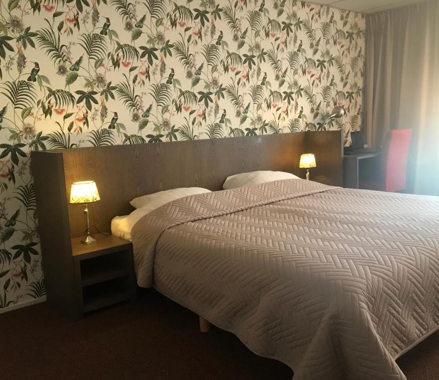 een slaapkamer met een bed met bloemenbehang bij Hotel Norg in Norg