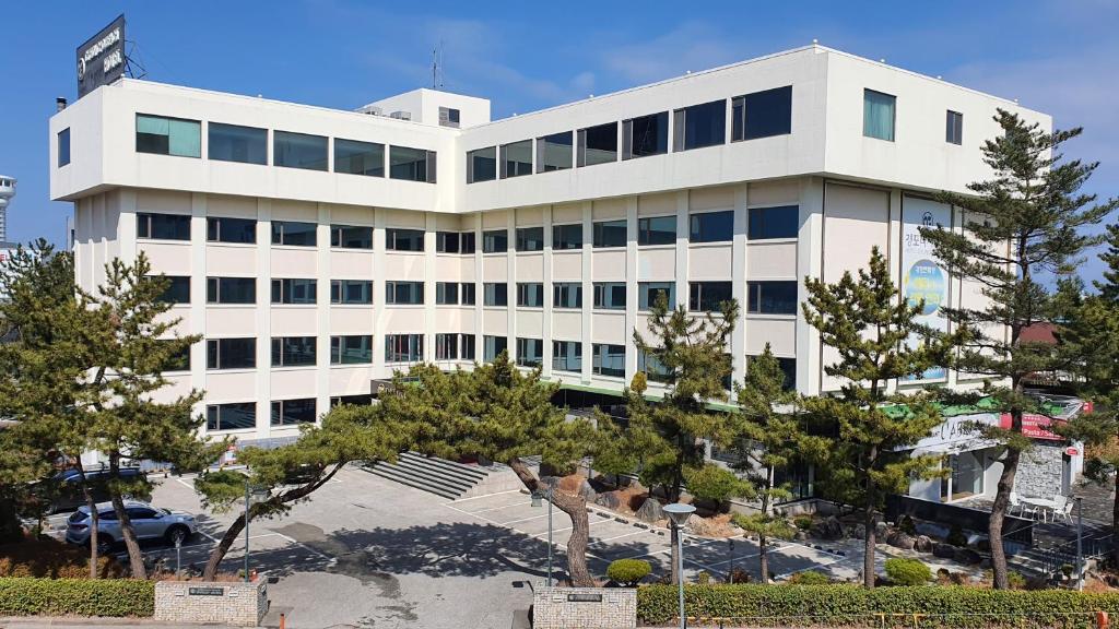 un edificio blanco con árboles delante de él en Gyungpo Beach Hotel, en Gangneung