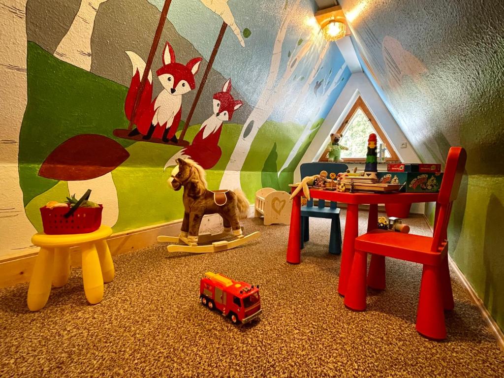 ein Kinderspielzimmer mit Spielzeugfahrzeugen und einem Tisch in der Unterkunft Haus am Berg - Pension direkt am Skihang in Kurort Oberwiesenthal