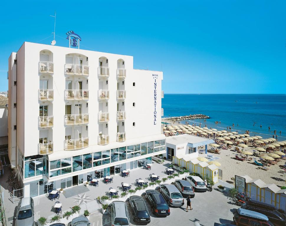 a hotel with a parking lot and a beach at Hotel International in Misano Adriatico