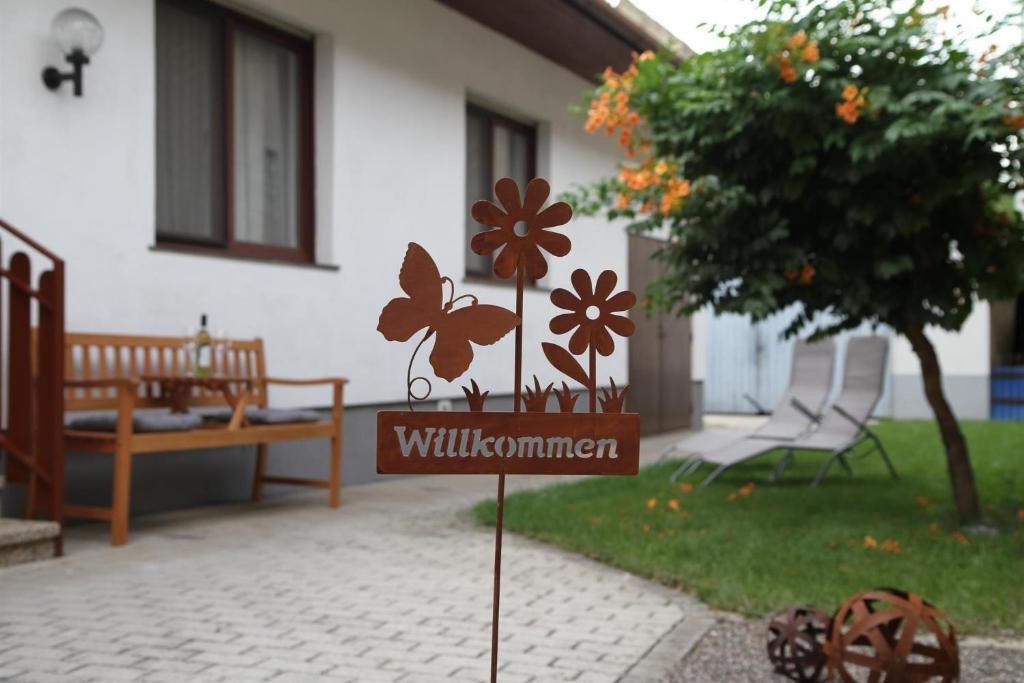 a sign in front of a house with flowers on it at Ferienwohnung Illy in Illmitz