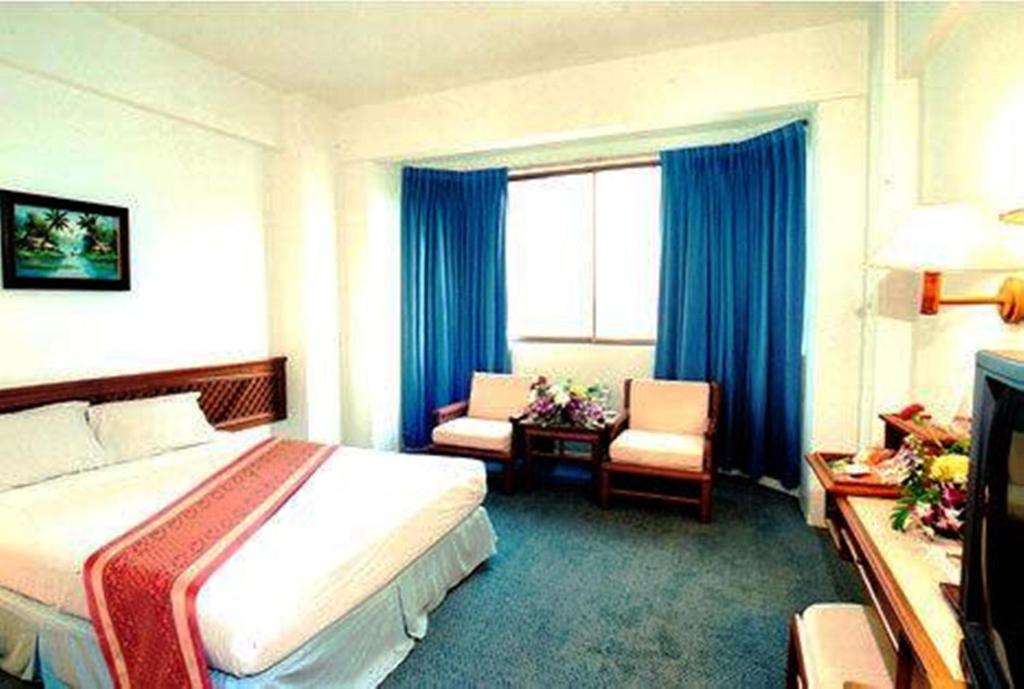 Habitación de hotel con cama y silla en The Regency Hotel Hatyai, en Hat Yai