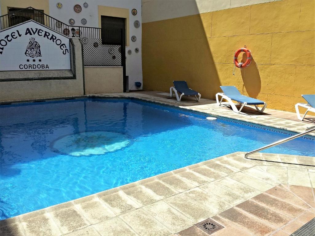 a large swimming pool in a hotel with two chairs at Hotel Averroes in Córdoba