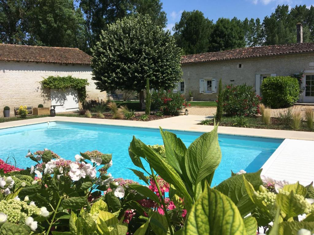 une piscine en face d'une maison ornée de plantes dans l'établissement Le Logis de la Soloire, à Nercillac