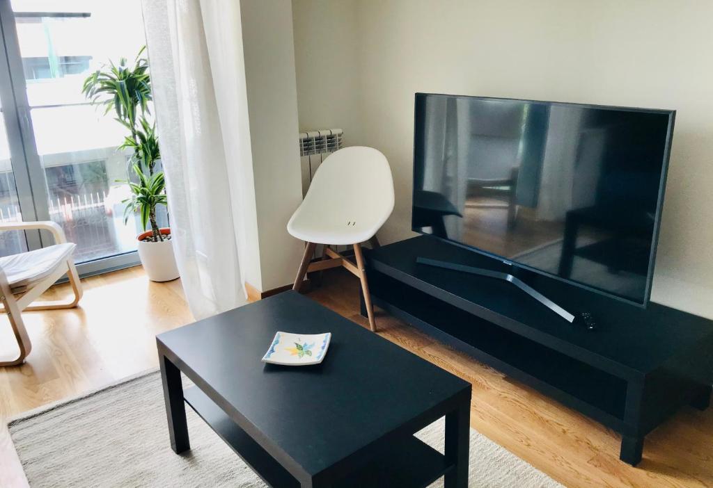 a living room with a black table and a tv at Apartamento Centro Histórico in Pontevedra