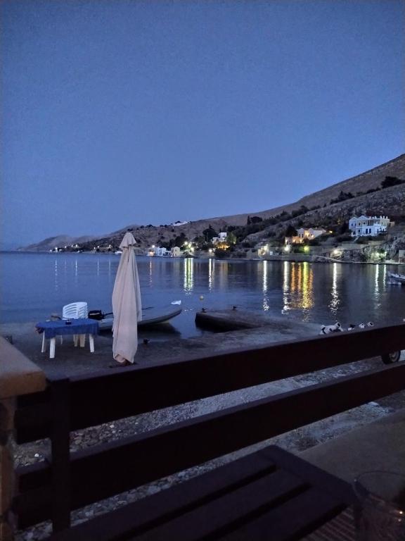 a table with an umbrella and a boat on the water at Symi . VILLA CALME (Sur la Mer). in Symi
