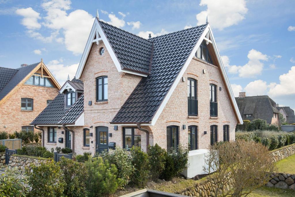 una grande casa in mattoni con tetto nero di Hüs Maxi a Wenningstedt