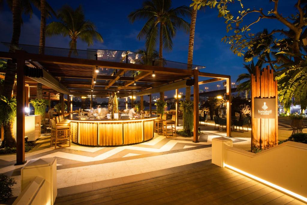 a restaurant with a bar on a deck at night at Anantara Riverside Bangkok Resort in Bangkok
