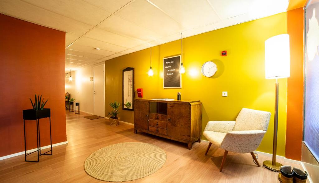 a living room with a chair and a clock on the wall at Kulkuri hostellit Hämeenlinna in Hämeenlinna