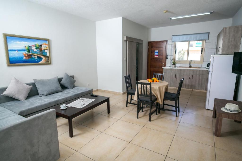 a living room with a couch and a table and a kitchen at Crystallo Apartments in Paphos