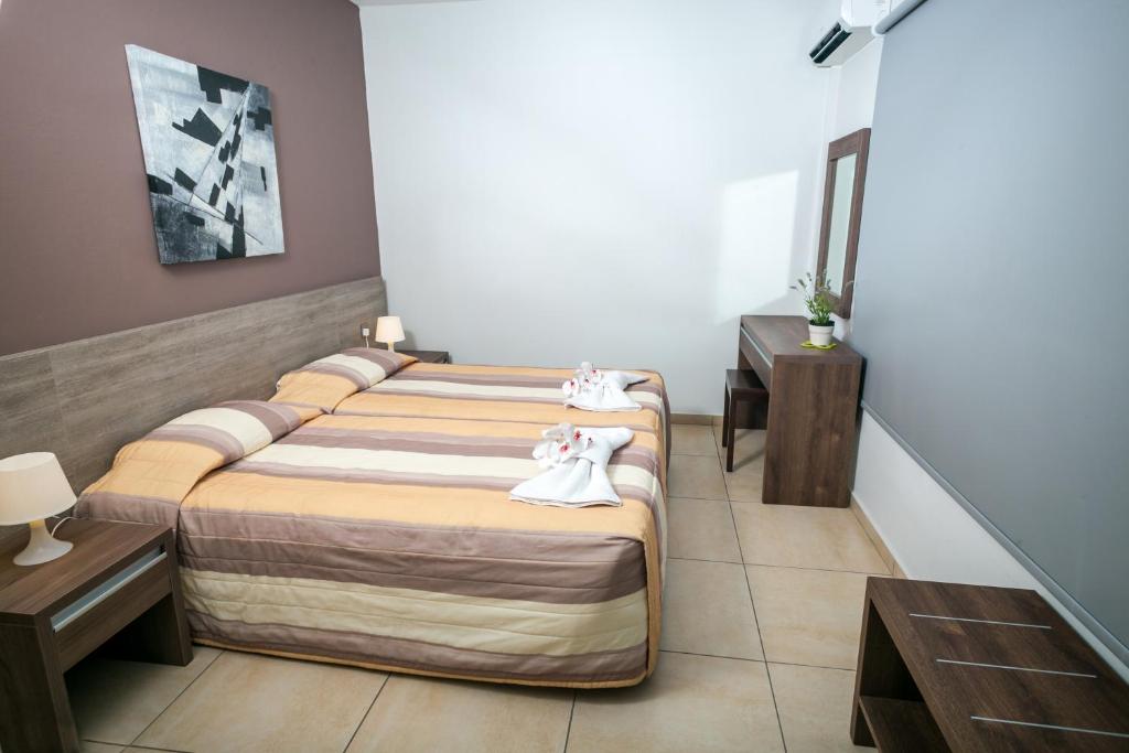 a hotel room with two beds and two tables at Crystallo Apartments in Paphos