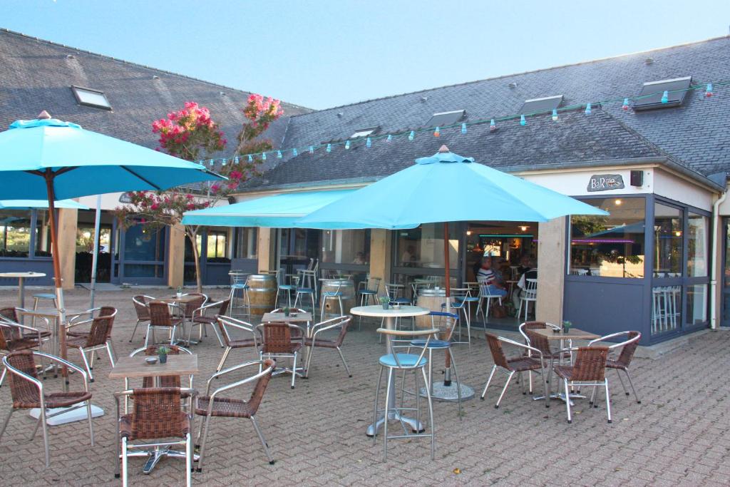 un patio extérieur avec des tables, des chaises et des parasols dans l'établissement Azureva Kerjouanno, à Arzon