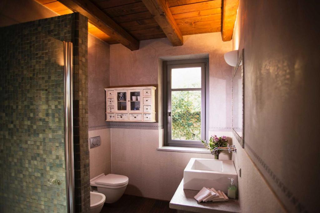 a bathroom with a sink and a toilet and a window at Cascina Canée in Angera