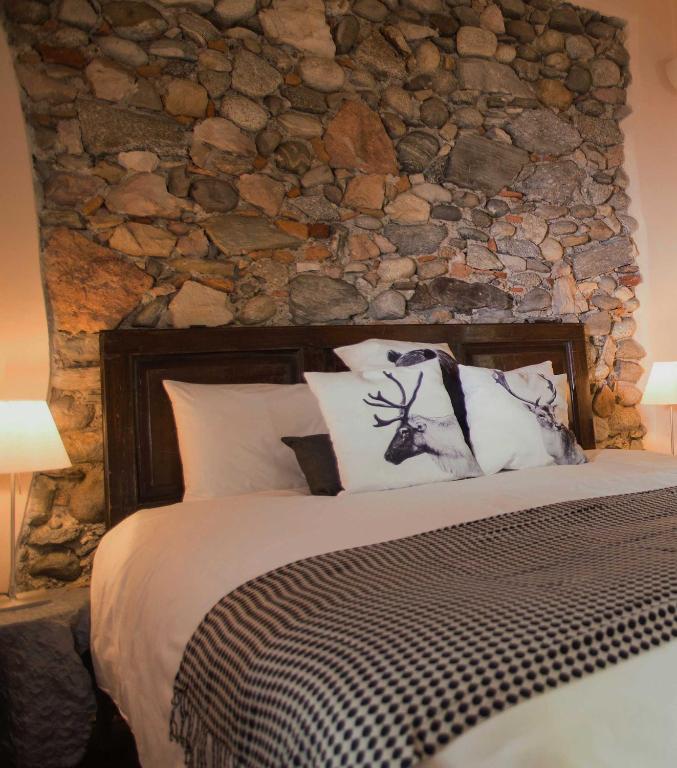 a bedroom with a stone wall and a bed with pillows at Cascina Canée in Angera
