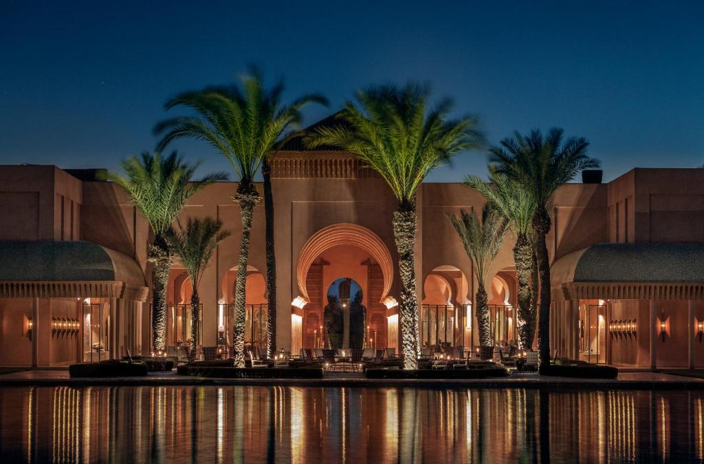 un complexe avec des palmiers en face d'un bâtiment dans l'établissement Amanjena Resort, à Marrakech