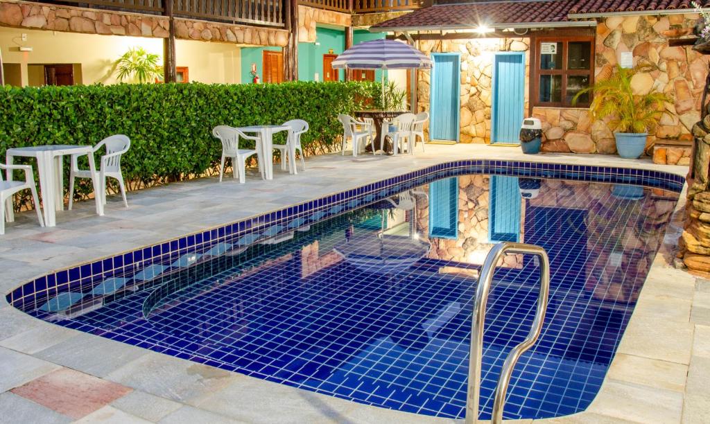 a swimming pool with chairs and a table at Pousada Vila Velha in Pirenópolis