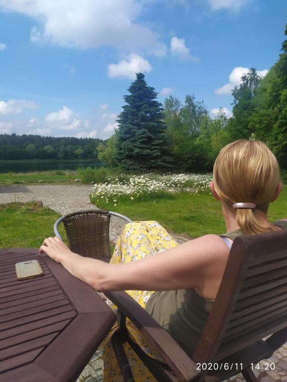 een vrouw op een stoel aan een picknicktafel bij Agroturystyka Wilczyn Cegielnia in Wilczyn