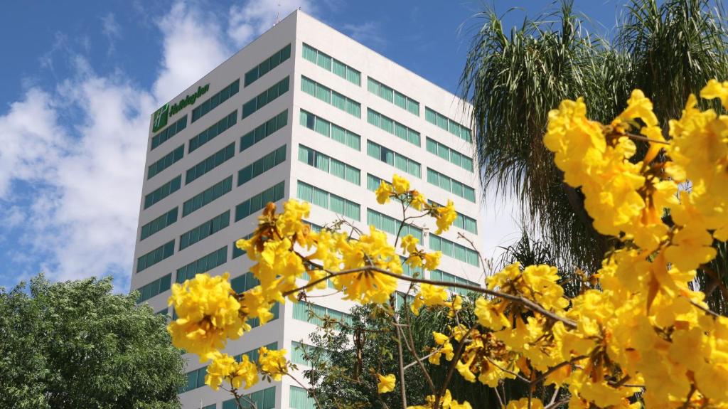 Un grand bâtiment avec des fleurs jaunes devant lui dans l'établissement Holiday Inn San Luis Potosi-Quijote, an IHG Hotel, à San Luis Potosí