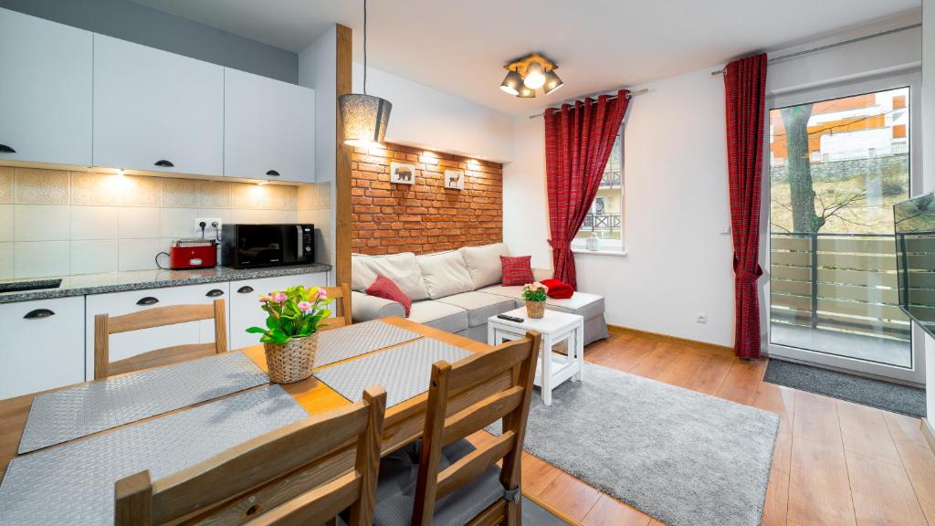 a kitchen and living room with a table and a couch at Apartamenty EverySky - Nad Łomnicą 1E-2B in Karpacz