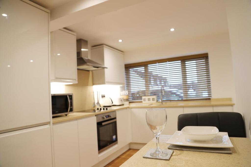 a kitchen with a table with a wine glass on it at Letting Serviced Apartments - Sheppards Yard, Hemel Hempstead Old Town in Hemel Hempstead