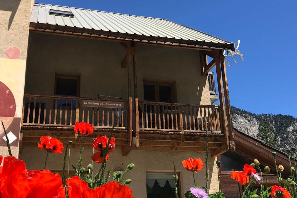 a building with a balcony with red flowers at Le Balcon des Charmottes in Névache