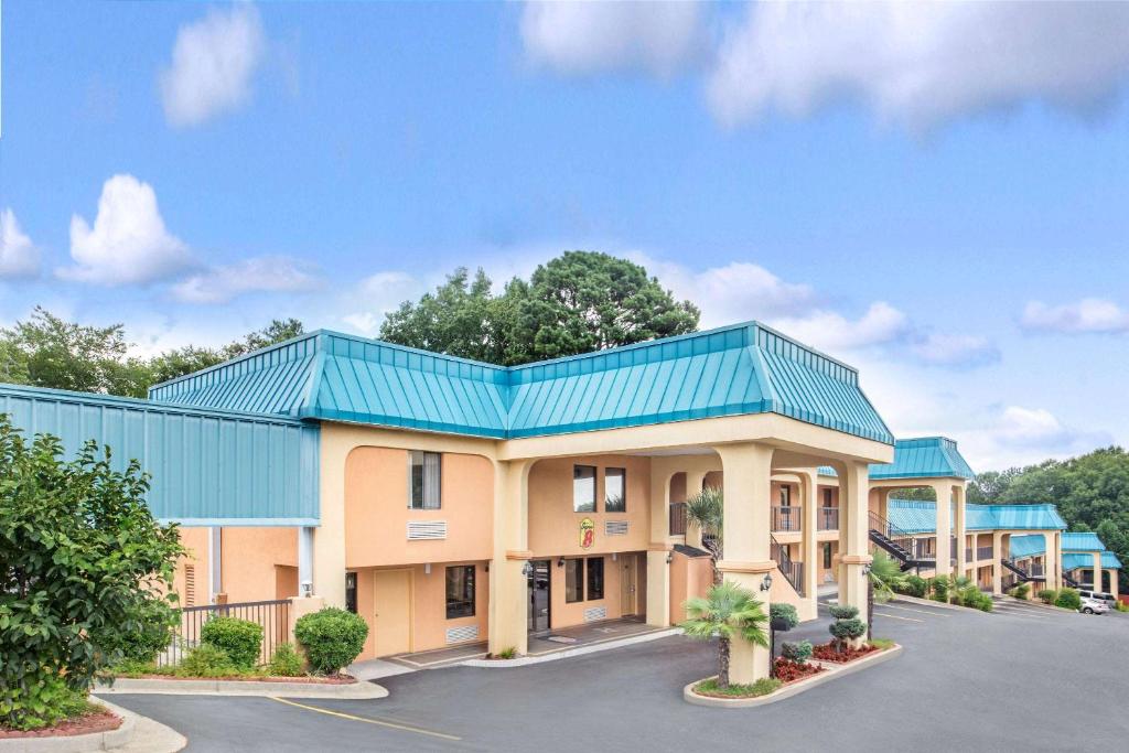 a hotel with a blue roof and a parking lot at Super 8 by Wyndham Forest Park in Forest Park